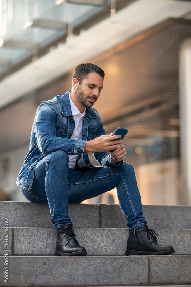 Cosmopolitan handsome man using mobile device and headphones