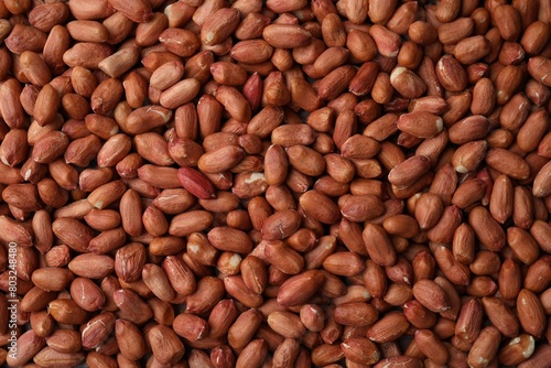 Many fresh unpeeled peanuts as background, top view