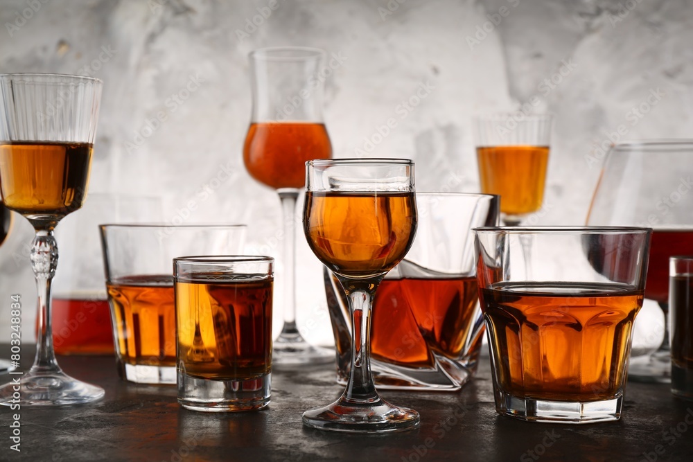 Different delicious liqueurs in glasses on grey table Different delicious liqueurs in glasses on grey table