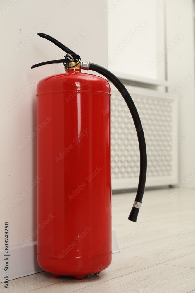 Obraz premium Fire extinguisher on floor near light wall indoors