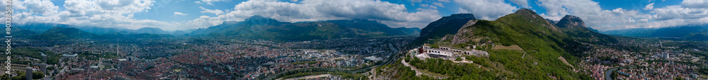 Obraz premium Aerial view of Grenoble's Bastille fort, city skyline crossed by the river and surrounded by mountains. France