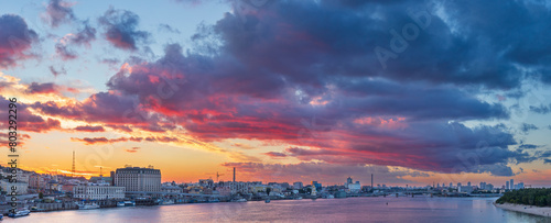 Picturesque dramatic clouds at sunset over the city embankment and the Dnieper river.