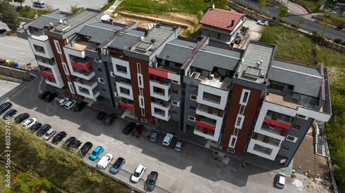 Aerial view of a modern gray and red building with windows and balconies.
