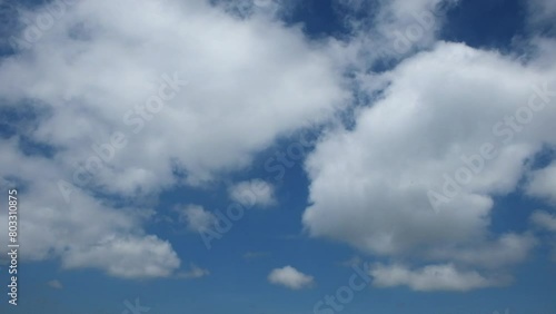 Timelapse of white clouds rolling fast.Clumpy clouds moving fast. Bright blue sky background.Sunny daytime with white clouds photo