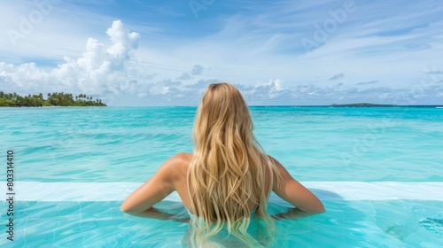Young woman unwinding in the serene pool of a luxurious resort, enjoying leisure time © Ilja