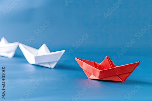 Red origami paper boat leads row of white on blue water, creative arts craft © Alexei