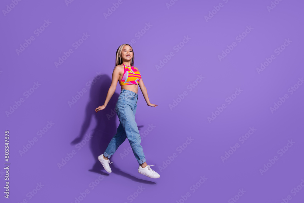 Photo of positive lovely girl wear trendy clothes walk travel empty space isolated on purple color background Photo of positive lovely girl wear trendy clothes walk travel empty space isolated on purple color background