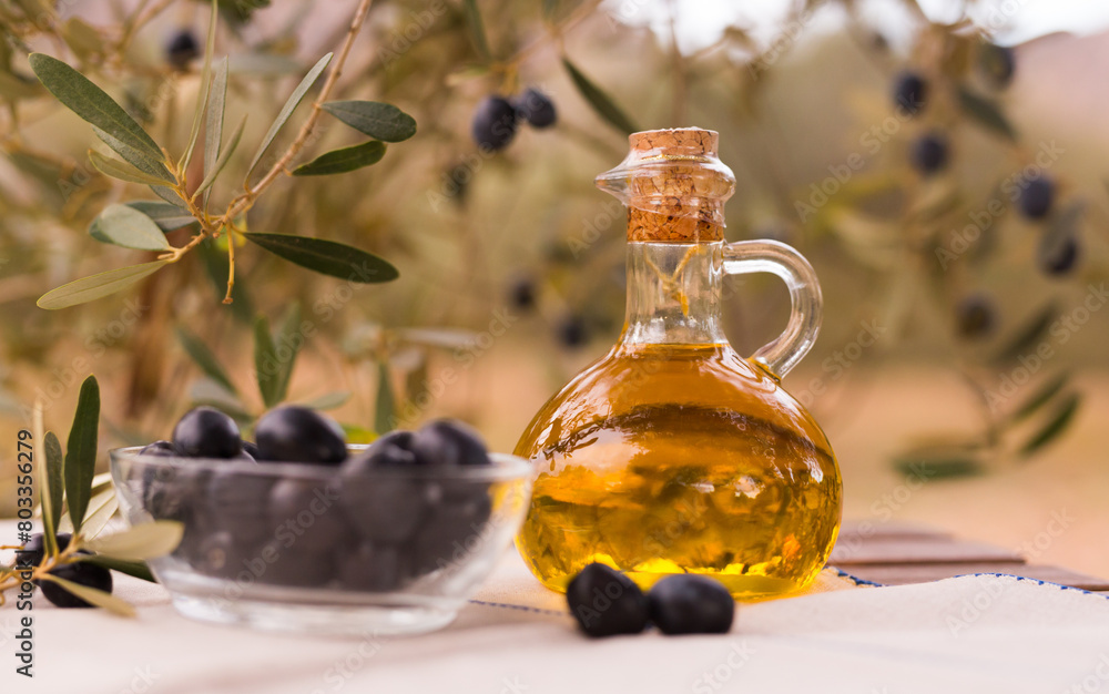 Still life of olives and oil on a table against a background of olive trees Still life of olives and oil on a table against a background of olive trees