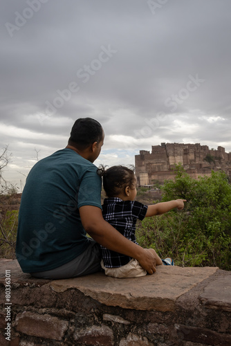 father with infant son watching historical fort at cloudy day