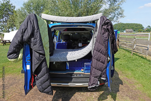 Schlafsack und Matratze trocknen an der Heck Tür eines Mini Camper Van am Morgen in der Sonne photo