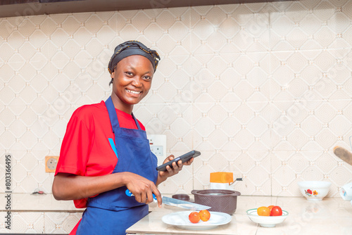 Young Black Female Cook Smiling with Phone and Knife - Culinary Portrait photo