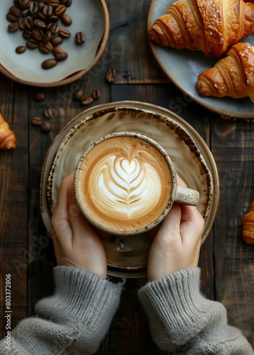 Hands holding coffee cup with beautiful latte art and plate of croissants on dark wooden table, flat lay composition. top view. Banner for magazine cover photo