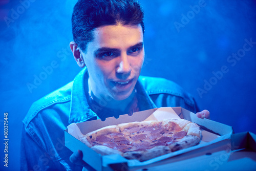 Young happy guy with pepperoni pizza in a cardboard box