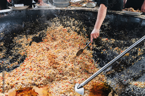 hands of a male cooking traditional oriental Arabic Uzbek rice pilaf in a cauldron. Central Asian Pilaf Center in Uzbekistan in Tashkent