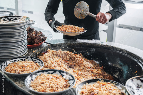 male hands chef cooking traditional oriental Arabic Uzbek pilaf with meat in a cauldron. Central Asian Pilaf Center in Uzbekistan in Tashkent