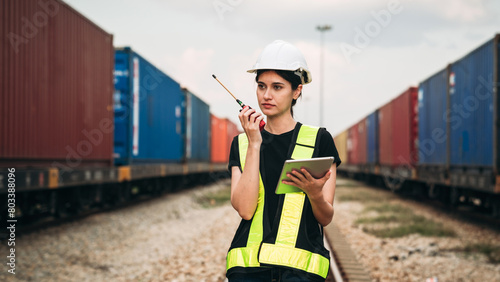 Supervisor inspecting inventory or task information on freight train cars and shipping containers. This pertains to logistics, including the import and export sectors. photo