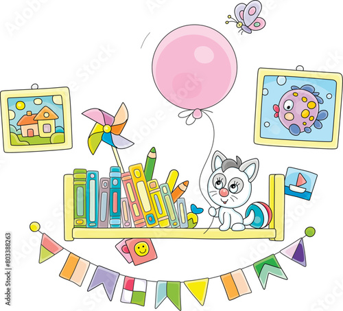 Funny little kitten sitting on a decorated bookshelf with children’s books and playing with a big pink balloon and merry butterfly flying around, vector cartoon illustration on a white background