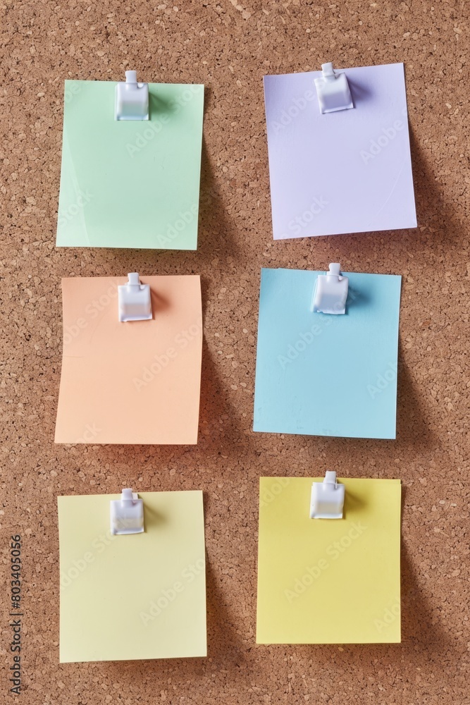Six blank pastel-colored post-it notes are pinned neatly to a brown cork board
Six blank pastel-colored post-it notes are pinned neatly to a brown cork board