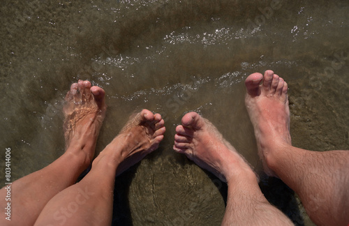 Male and female feet on a sandy beach. Vacation concept.