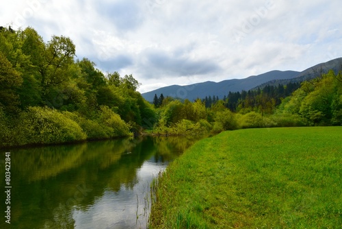 View of Rak river and grassy plains next to it with Javorniki mountains behind at Rakov Škocjan, Notranjska, Slovenia