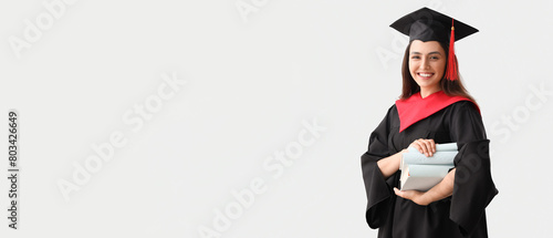 Female graduate student with books on light background