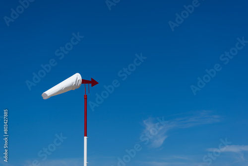 white windsock with a red arrow pointing to free space in the sky