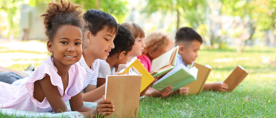 Cute little children reading books in park