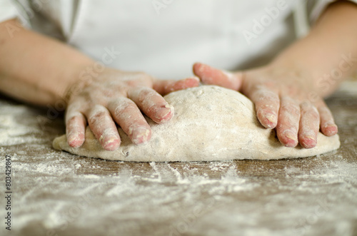 Handcrafting loaves of bread dough. Process occurs in a bakery. The dough is kneaded by warm hands.