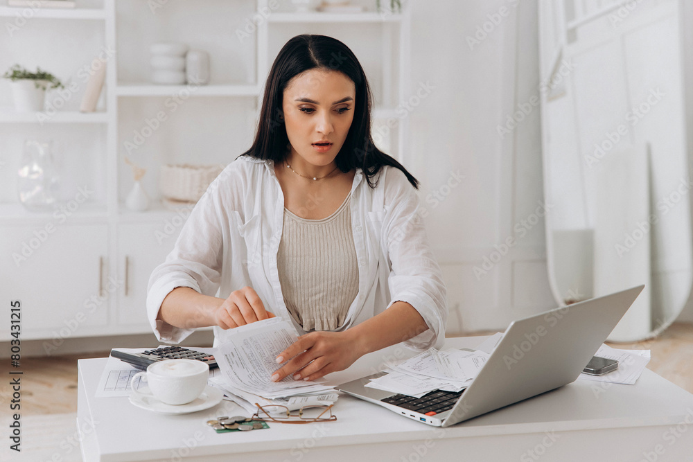 Frightened by tax filing error, young woman pores over financial documents, reflecting real-world challenges in personal finance management, suitable for educational finance platforms Frightened by tax filing error, young woman pores over financial documents, reflecting real-world challenges in personal finance management, suitable for educational finance platforms