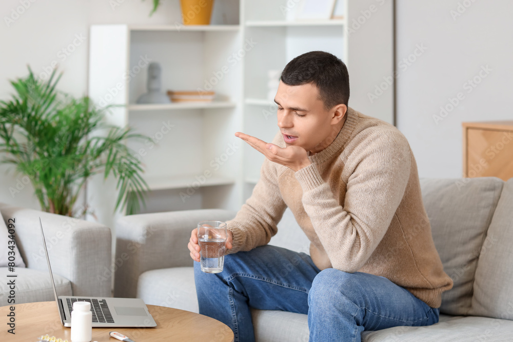 Ill young man taking pill while video chatting with doctor at home Ill young man taking pill while video chatting with doctor at home