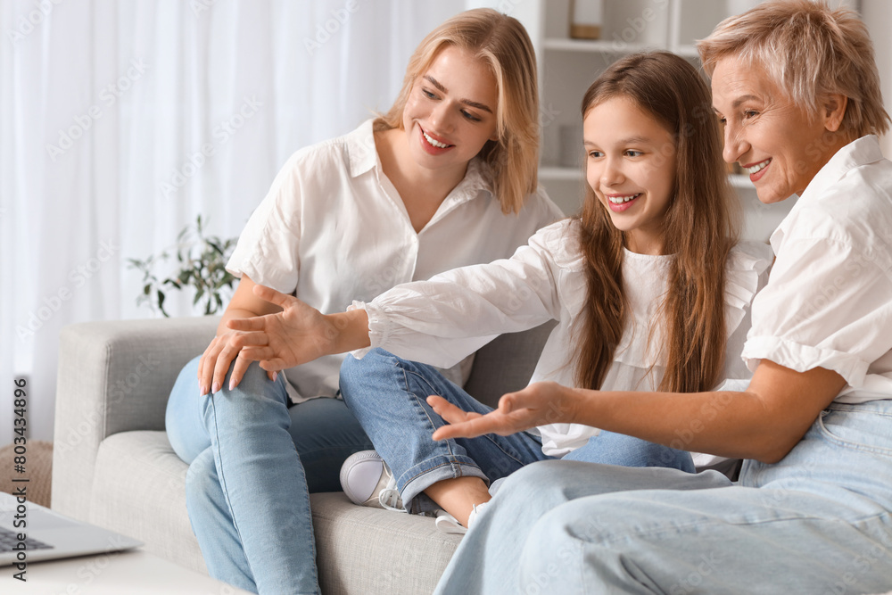 Little girl with her mom and grandmother video chatting at home