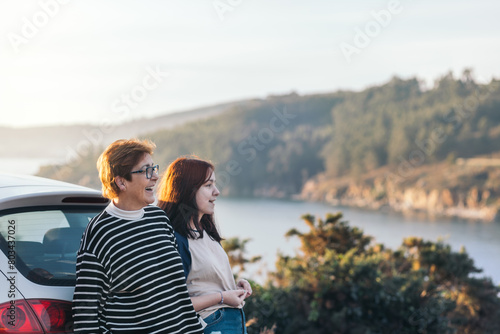 Portrait of a mother and daughter chatting and smiling while taking a break from a road trip at a beautiful location