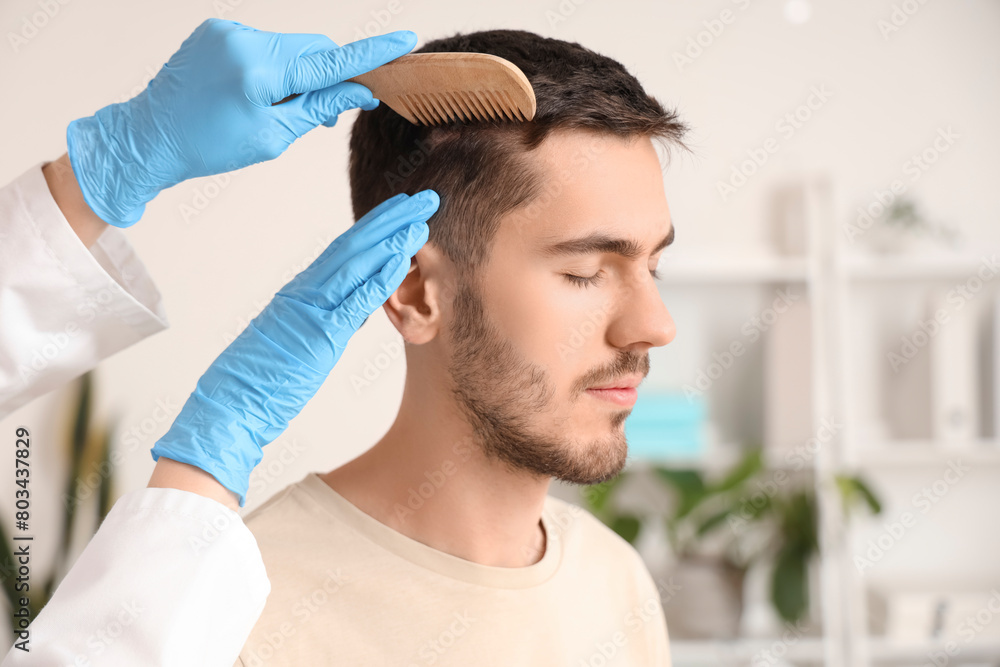 Doctor combing young man's hair in clinic, closeup Doctor combing young man's hair in clinic, closeup