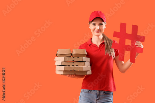 Female courier with pizza boxes, food containers and hashtag sign on orange b...