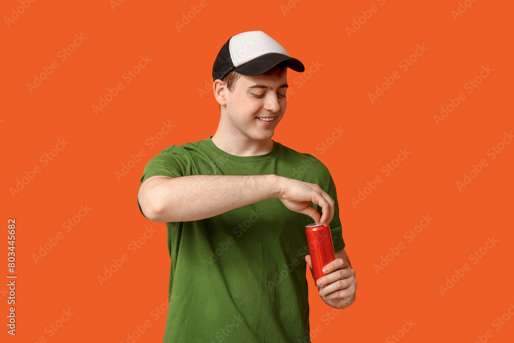 Young man with can of soda on orange background Young man with can of soda on orange background