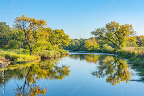 A tranquil image of a meandering river reflecting the clear blue sky, with trees lining its banks and creating a serene, natural setting.