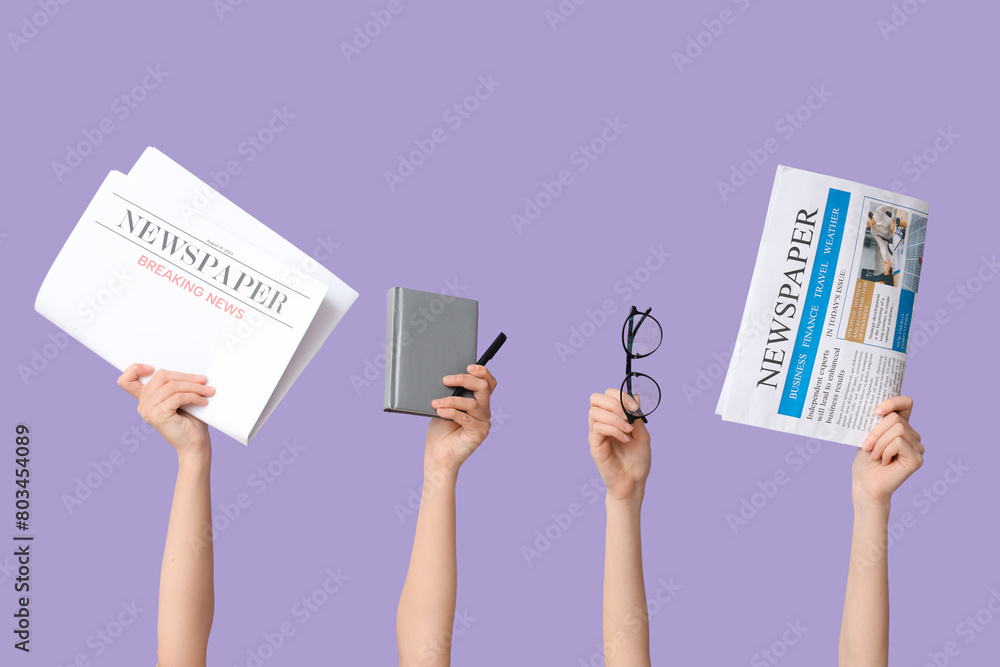 Female hands with newspapers, notebook and eyeglasses on lilac background Female hands with newspapers, notebook and eyeglasses on lilac background