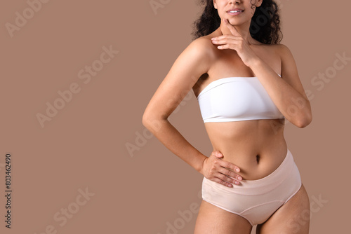 Young woman in menstrual panties on brown background, closeup © Pixel-Shot