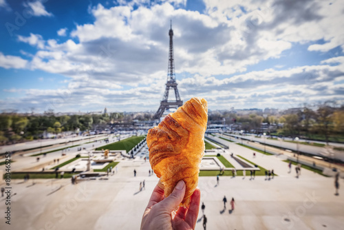 Obraz na płótnie A hand holding a french Croissant in front of the Eiffel Tower in Paris as trave