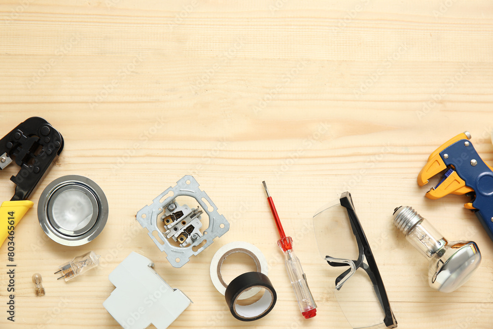 Electrician's tools and light bulbs on wooden background