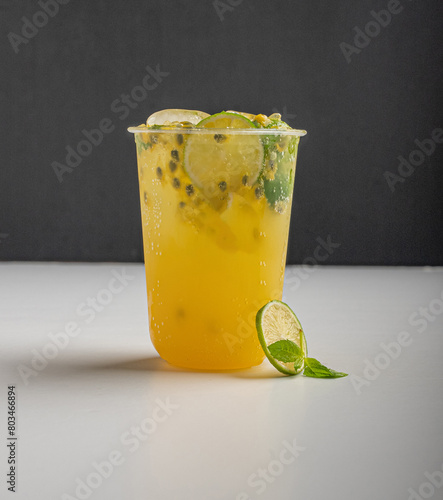 A glass of passion fruit mojito with slice of lime and mint leaf on table