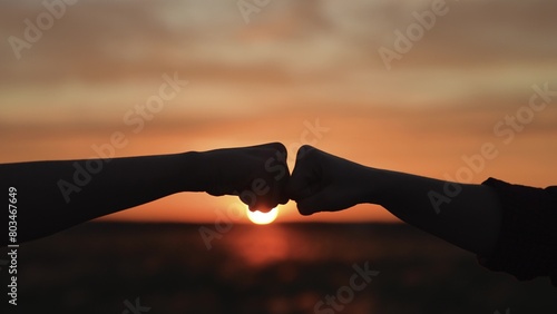 Hands clashing fists brofist at sunset. Bump clash of two fists. Confrontation competition. Gesture of giving respect approval. Teamwork friendship partnership working together at agricultural farm.