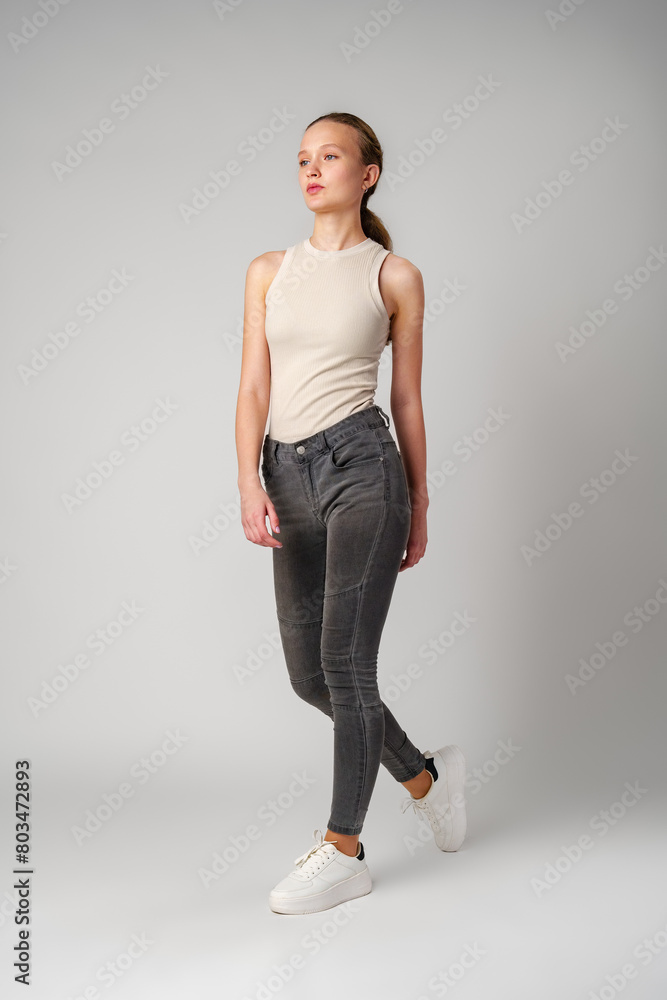 Girl in Beige Tank Top and Grey Jeans on gray background Girl in Beige Tank Top and Grey Jeans on gray background