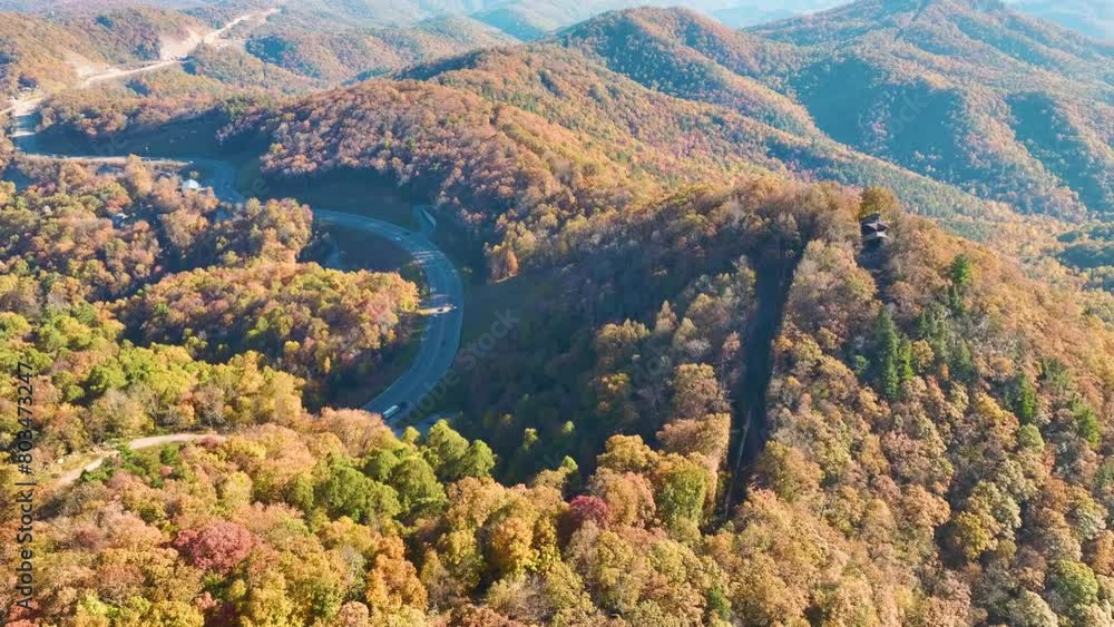 Wide highway road in North Carolina leading through Appalachian mountains with yellow fall forest and fast moving traffic. Scenic route in US national park area
