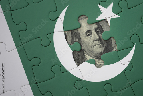 puzzle with the national flag of pakistan and usa dollar banknote. finance concept