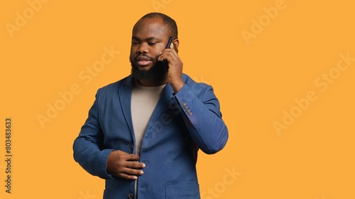 African american man disagreeing with friend during telephone call, shaking head, studio background. BIPOC person talking on phone with mate, unhappy with proposal, refusing, camera A photo