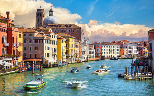 Grand Canal in Venice Italy. Panoramic view to picturesque landscape city and cathedral Dome. Motorboats cutters on water. Sunny summer day with blue sky sunset dramatic clouds