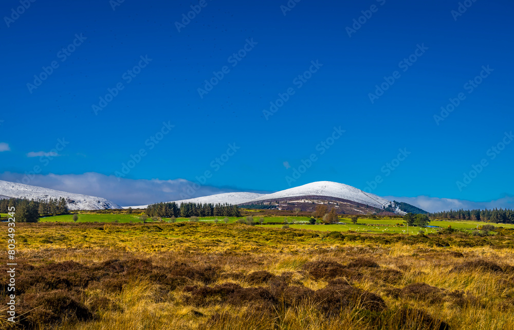 Naklejka premium Snow-Capped Majesty: Djouce Mountain Standing Tall under a Clear Blue Sky