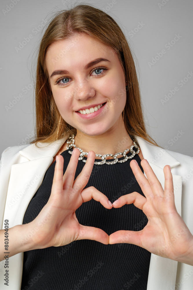 Woman Making Heart With Hands on gray background