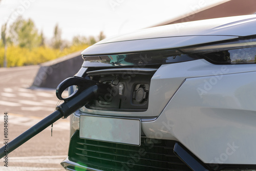 A white car at a gas station, filling up with gasoline